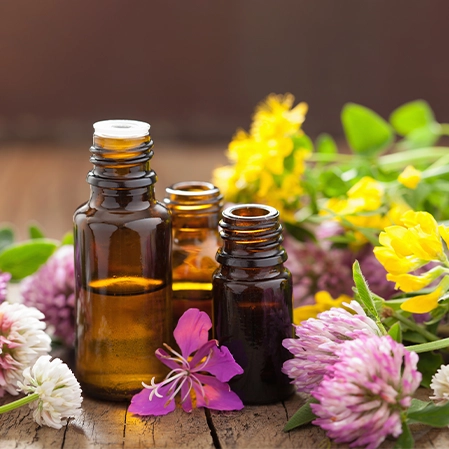 Collection of Essential Oils and flowers on a wooden surface