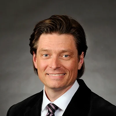 Chiropractor Cottage Grove WI Seth Anderson About Chiropractor Seth Anderson Smiling In Black Suit And Black/Purple Tie