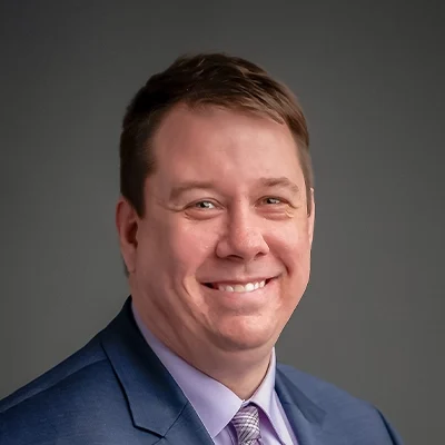 Chiropractor Fort Atkinson WI Luke Smith About Chiropractor Luke Smith Smiling In Navy Suit and Purple Shirt