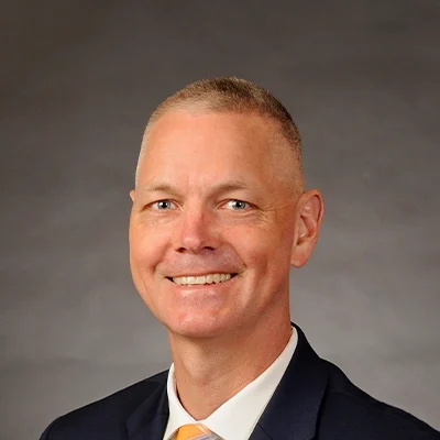 Chiropractor Fort Atkinson WI Todd Tesch About Chiropractor Todd Tesch Smiling In Navy Suit and Yellow Tie