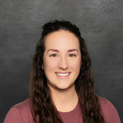 Chiropractor Ellie Ryan Smiling In Front Of Black Wall