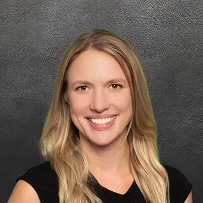 Chiropractor Emily Doudlah Smiling In Front Of Black Wall