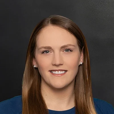 Chiropractor Jennifer Voelz Smiling In Front Of Black Wall