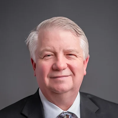 Chiropractor Stephen Dewitt Smiling In Grey Suit And Dress Shirt