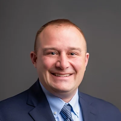 Chiropractor Benjamin Mikla Smiling In Navy Suit and Blue Shirt