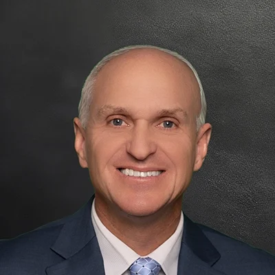 Chiropractor Nathan Considine Smiling In Front Of Black Wall