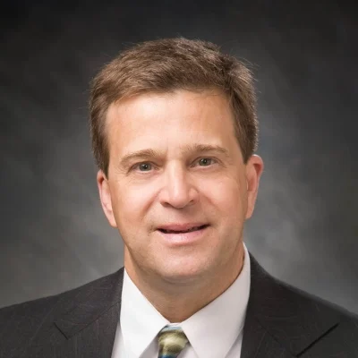 Chiropractor New Glarus WI Kelly Towne About Chiropractor Kelly Towne Smiling In Grey Suit And Colorful Tie