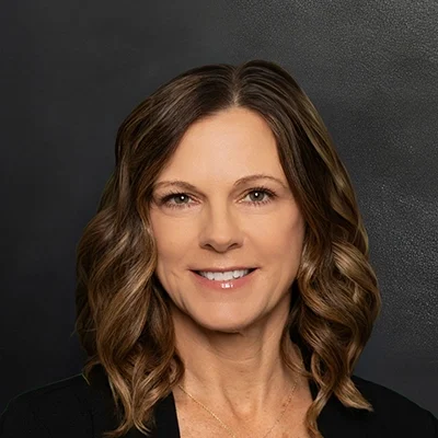 Chiropractor Amy Zimmerman Smiling In Front Of Black Wall