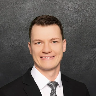 Chiropractor Brandon Wedig Smiling In Front Of Black Wall