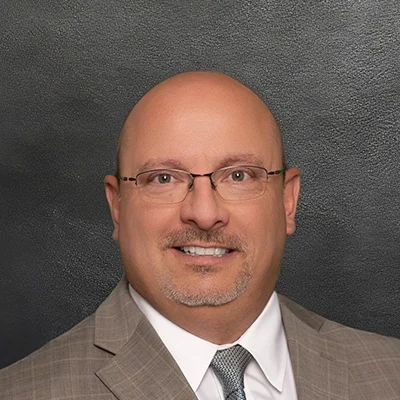 Chiropractor Jeffery Horkan Smiling In Front Of Black Wall