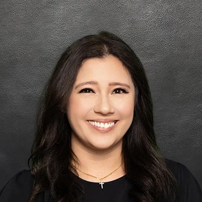 Chiropractor Michaela Powers Smiling In Front Of Black Wall