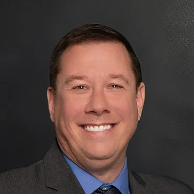 Chiropractor Luke Smith Smiling In Front Of Black Wall