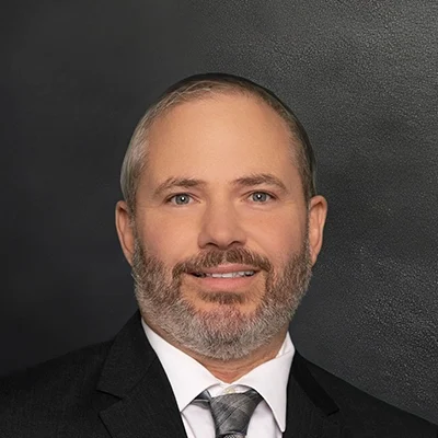 Chiropractor Paul Morovits Smiling In Front Of Black Wall